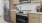 Large well lit kitchen with wood floors and stainless steel appliances.
