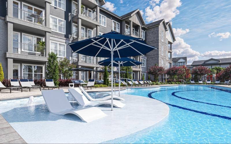 a pool with lounge chairs and umbrellas by a building